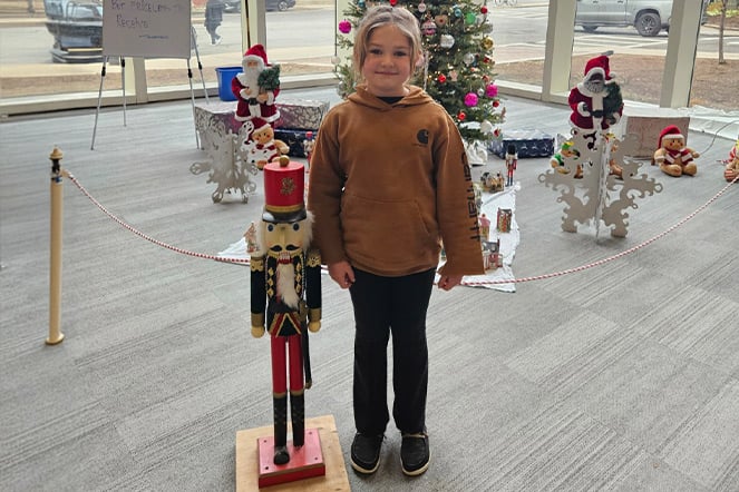 a child standing next to a holiday nut cracker