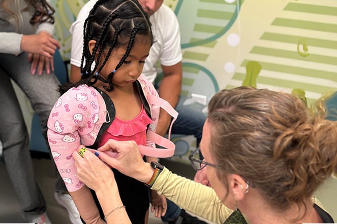 a woman makes adjustments to a child's prosthetic arm