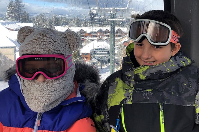 two children in ski attire on a ski lift