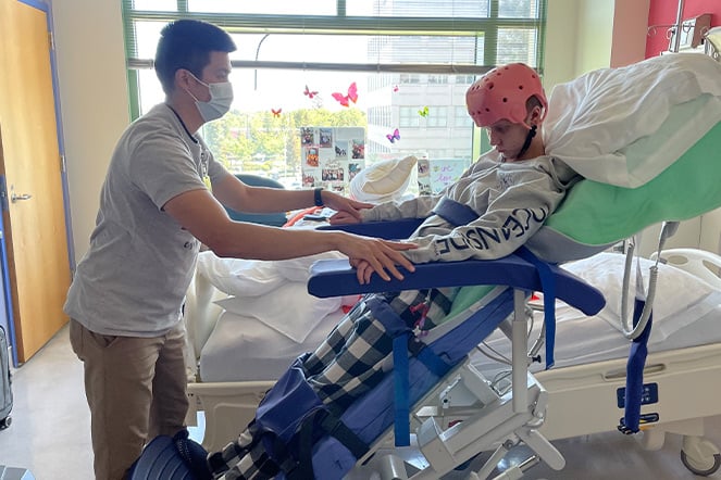 a man helps a child stand in their hospital bed