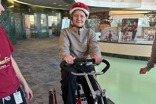 a child wearing a helmet and riding an adaptive bicycle