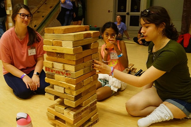 an adult and two children playing Jenga on the floor