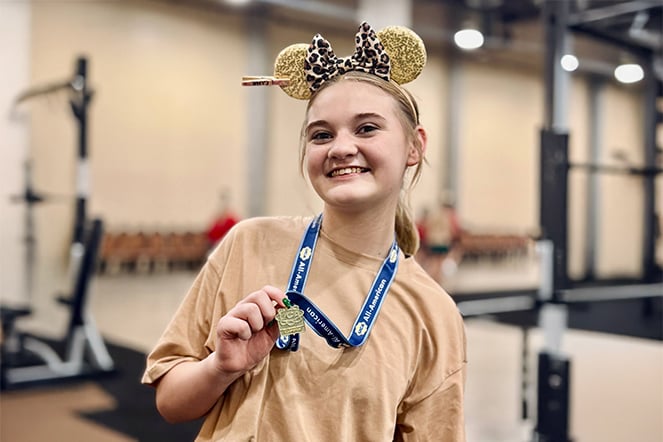 a cheerleader wearing Mickey Mouse ears holding a medal