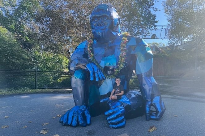 a child sitting with a large gorilla statue