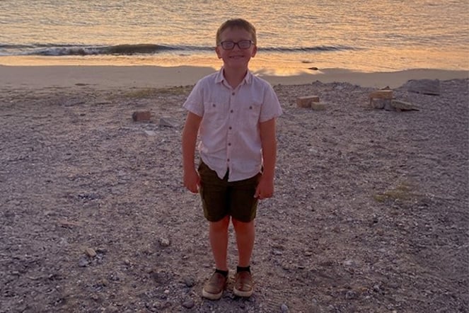 a child standing in front of a beach sunset