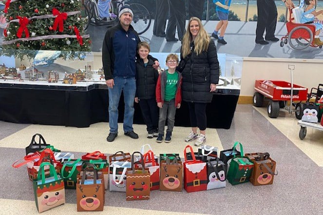 a family standing in front of a row of gift bags