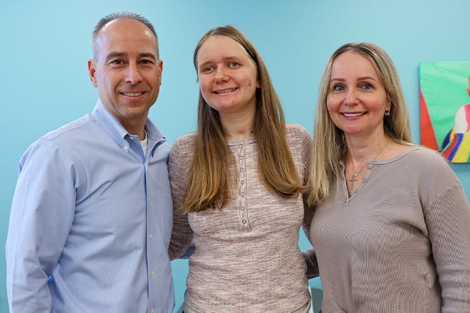 a man and a woman standing with a teenager