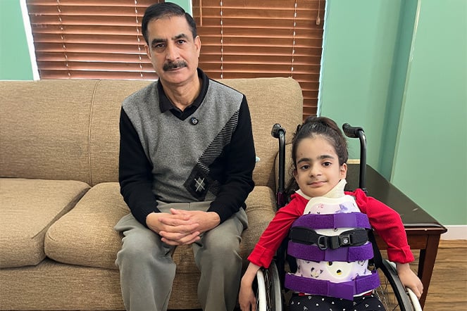 a man sitting on a couch next to a child in a wheelchair
