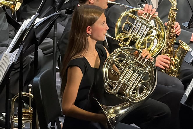 a girl playing the French horn in an orchestra