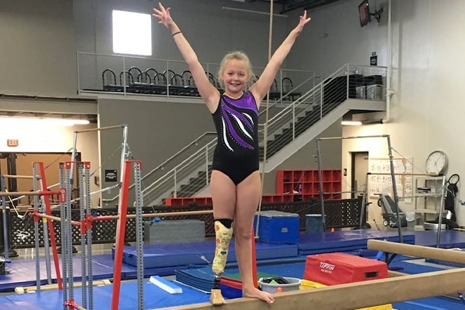 a gymnast with a prosthetic leg standing on a balance bean