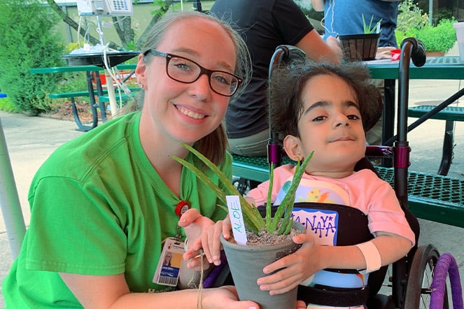 a woman kneeling next to a child holding a plant