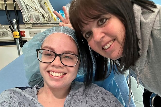 an adult standing next to a smiling child in a hospital bed