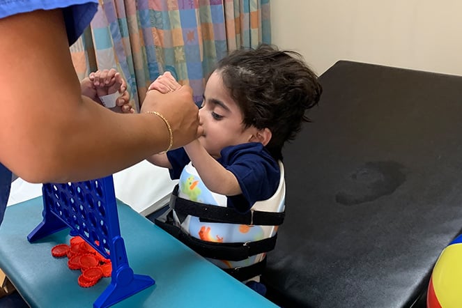 a child sitting up with the assistance of an adult