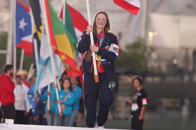 a teenager wearing a gold medal holding a flag