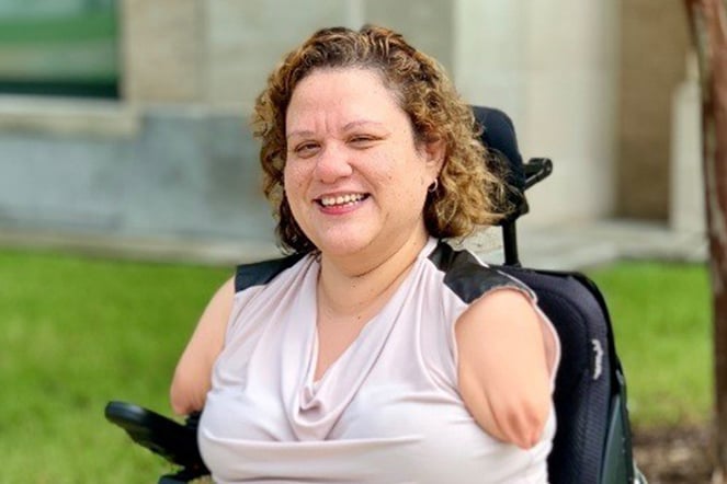 A woman with phocomelia smiling in a wheelchair