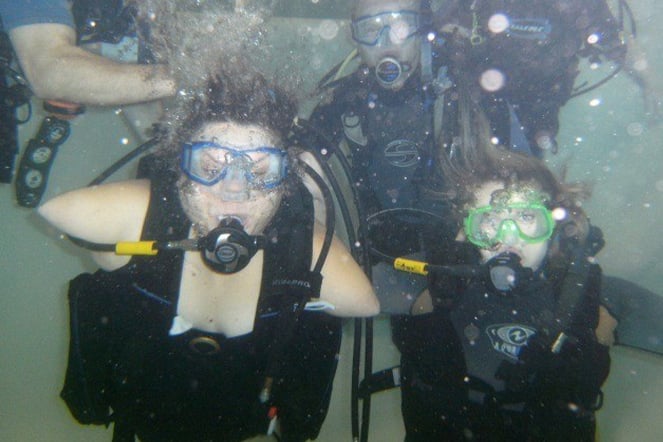 an underwater photo of a child with phocomelia scuba diving with a group of people