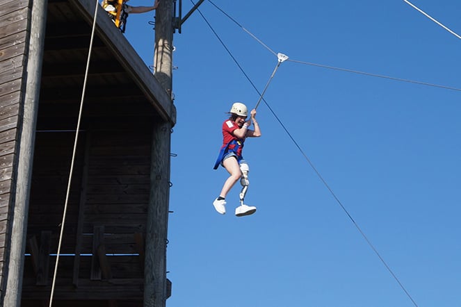 a child with a prosthetic leg on a zip line course