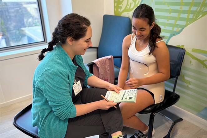 a healthcare professional speaks with a child in a scoliosis brace