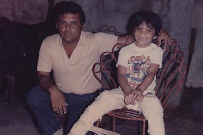 a man kneeling beside a smiling child with leg casts