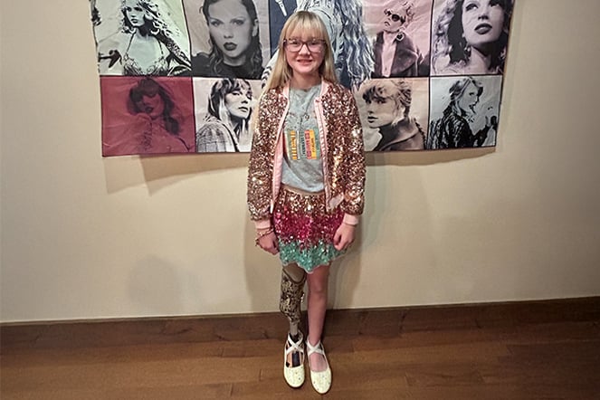 a child in a sparkling outfit in front of a Taylor Swift banner