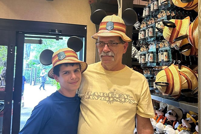 a father and son wearing hats with Mickey Mouse ears
