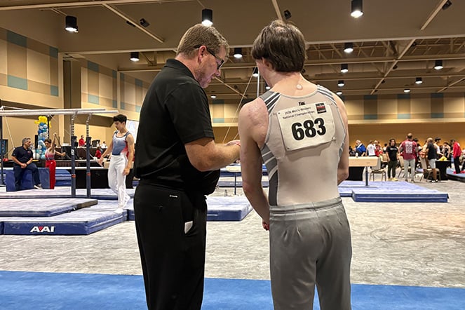a gymnast and their coach facing a gymnasium during a competition