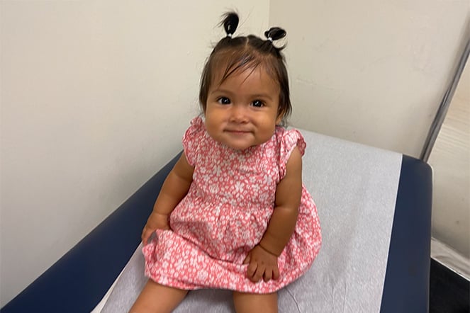 a smiling toddler sitting on in a doctor's office