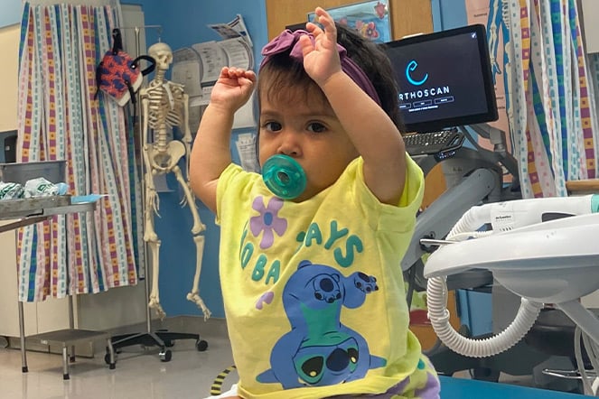 a baby raising their arms in a doctor's office