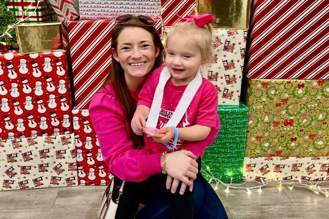 a woman holding a child in front of wrapped presents