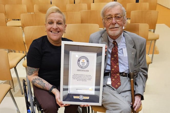 a woman in a wheelchair holding a plaque next to a man in a suit