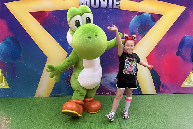 a child and Yoshi from the Super Mario Brothers movie waving their arms