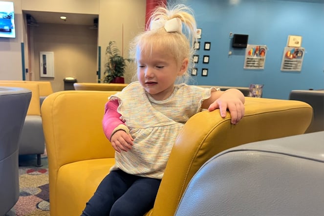 a child with an arm cast sitting in a large chair