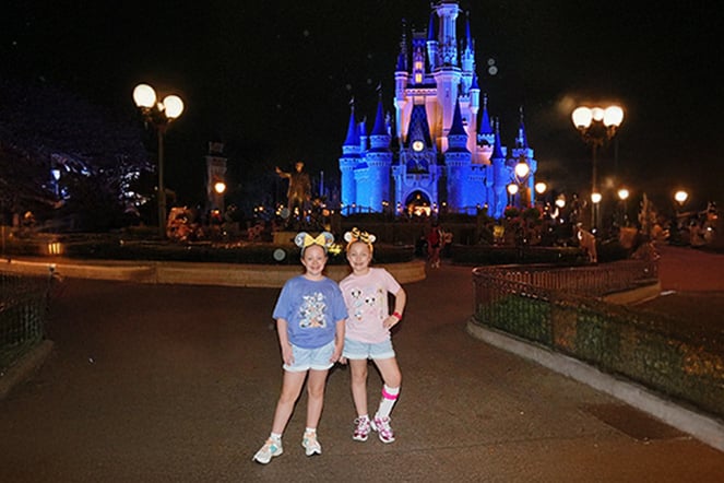 two children standing in front of a castle at Disney World