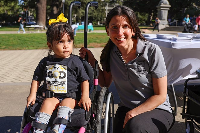 a woman kneeling next to a child in a wheelchair