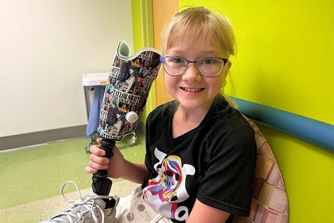 a child holding a prosthetic wrapped in images of Taylor Swift
