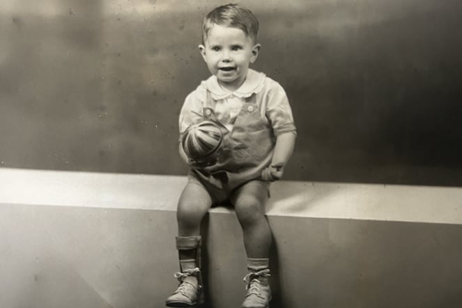 a black and white image of a child with a leg brace