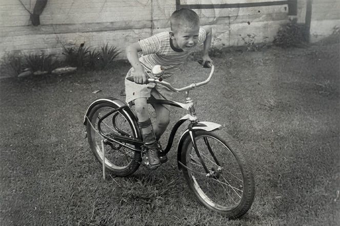 a black and white image of a child riding a bike