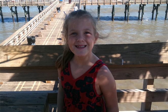 a child sanding on a dock in the shade