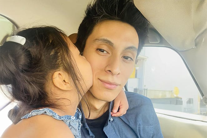 a daughter kissing her father on the cheek in a car