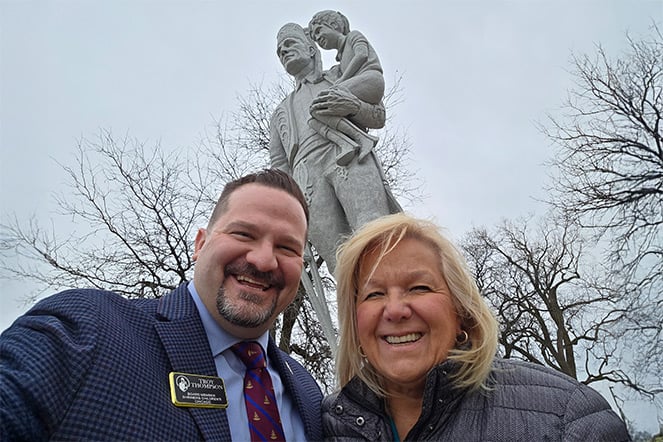 a couple taking a selfie in front of a large statue