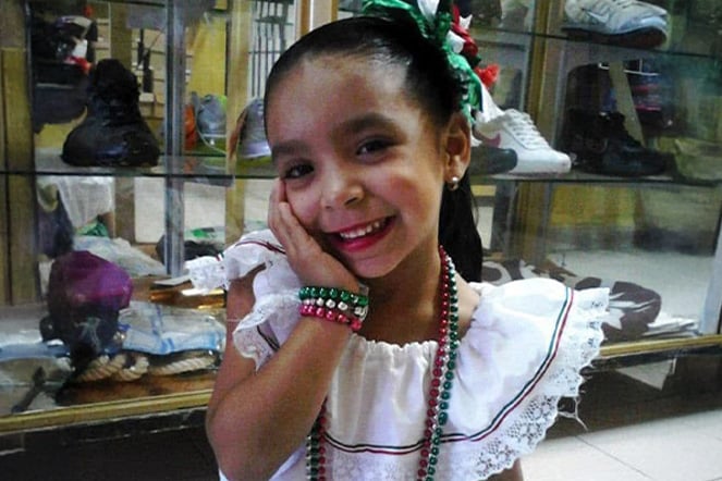 a young child smiling in front of a glass display