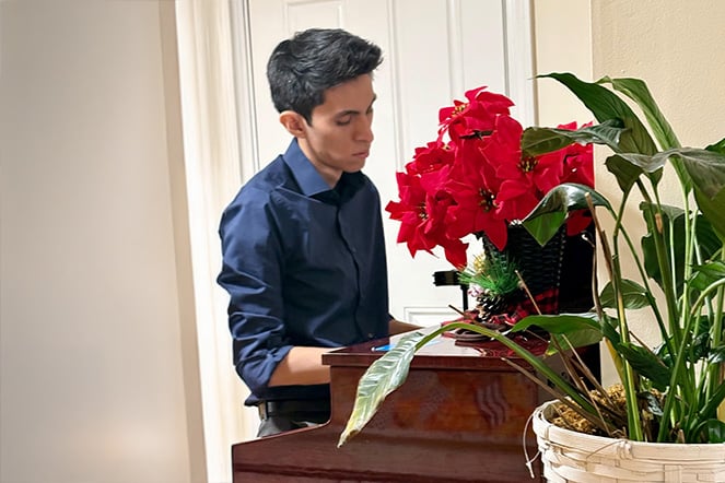 a pianist playing behind a pot of flowers