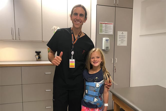 a healthcare provider stands next to a child in a scoliosis brace