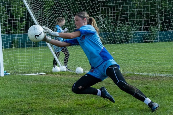 a soccer goalie stopping a ball 