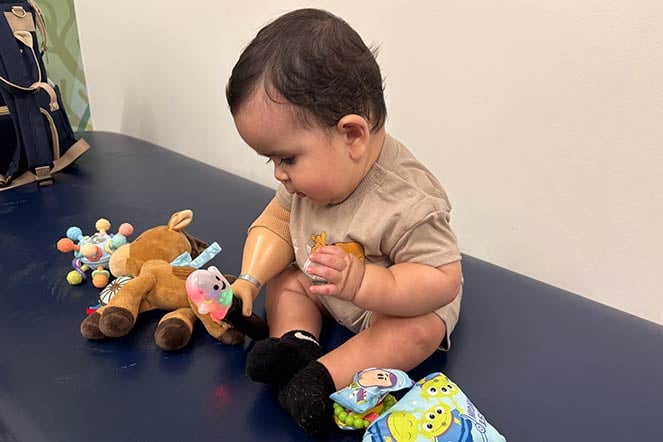 baby uses prosthetic arm to play with toys