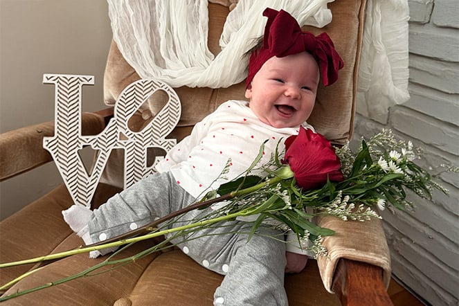 a young child sitting in a child with a bouquet of flowers and a sign that reads "LOVE"
