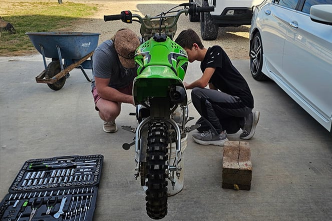 a father and son working on a motorcycle