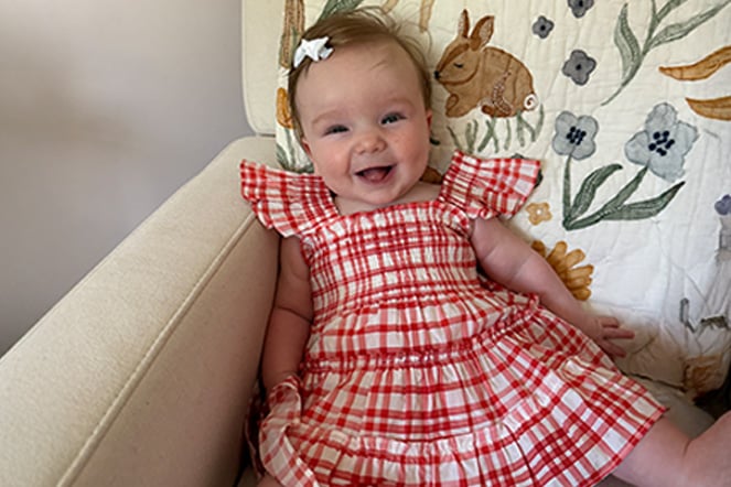 a smiling infant in a red dress