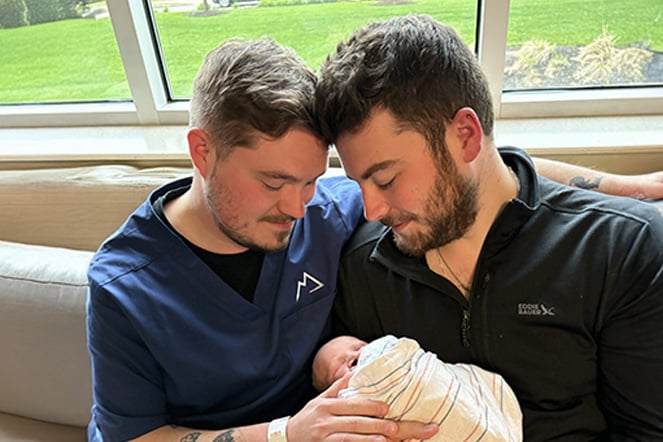 two men holding an infant