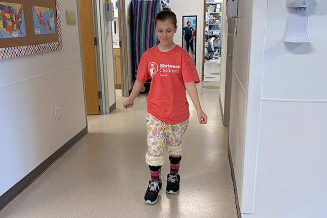 a child wearing leg braces walking in a hospital hallway